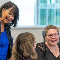 President Mantella smiling with two Alumni at the event.